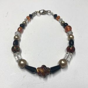 Handmade beaded bracelet in orange, black, and gold. Original design